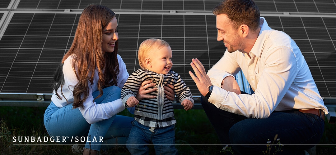 Child and parents in front of solar panels